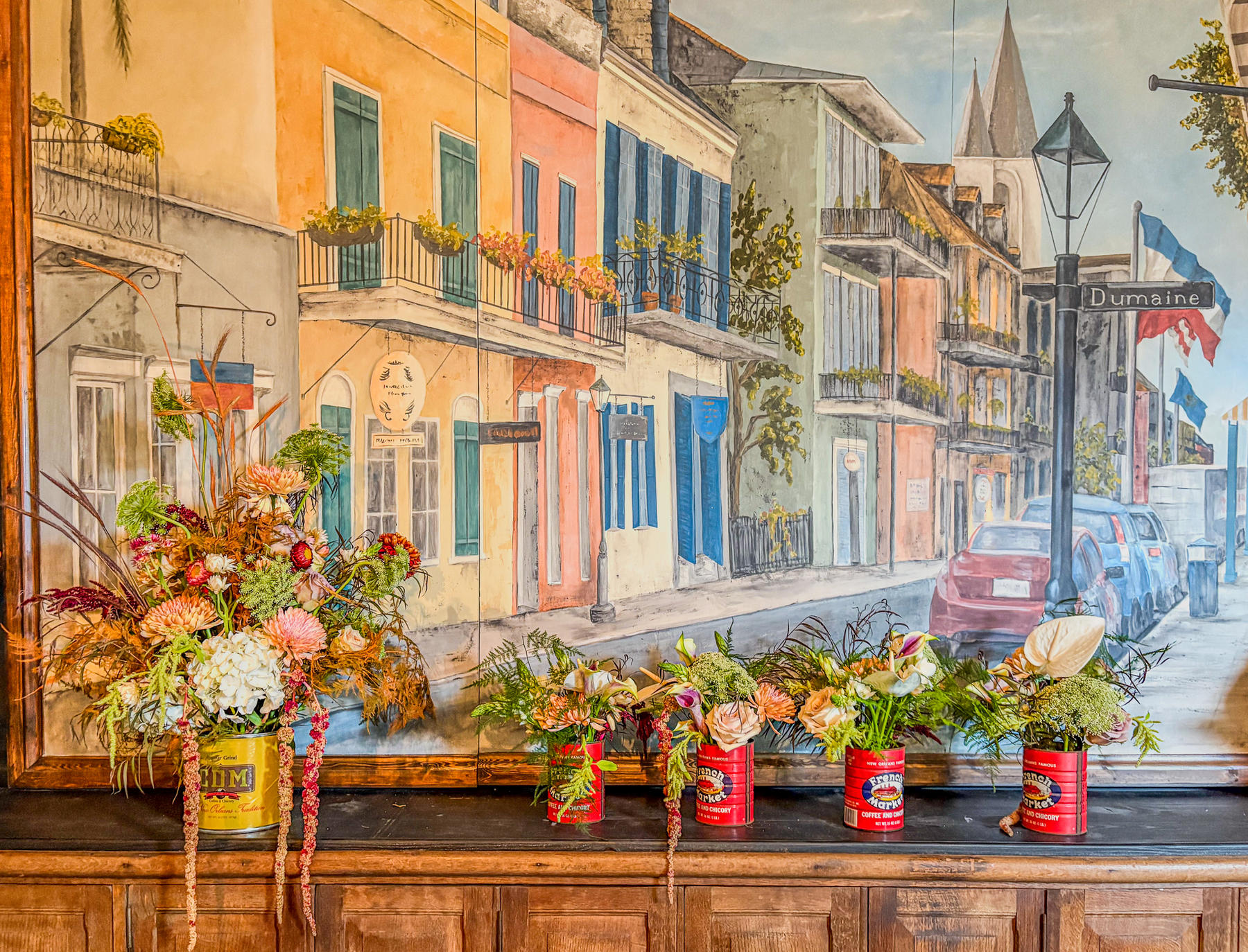 Arrangements in painted tins before a French Quarter mural